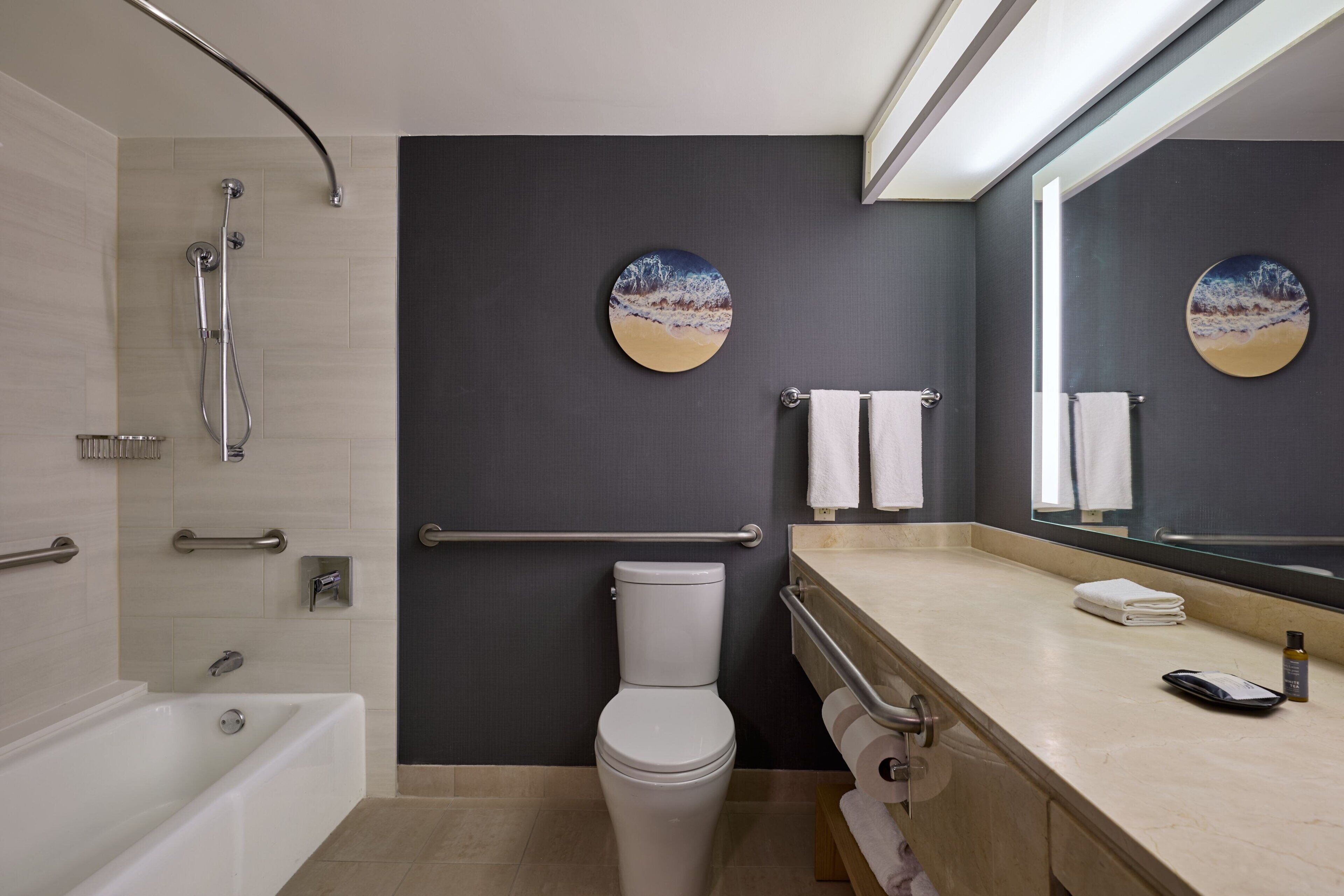 Et moderne badeværelse med badekar, toilet og et vaskebord med spejl.