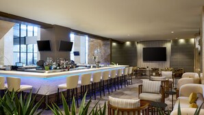 Un moderno bar con una barra larga, taburetes y una zona de estar con sofás y sillones.