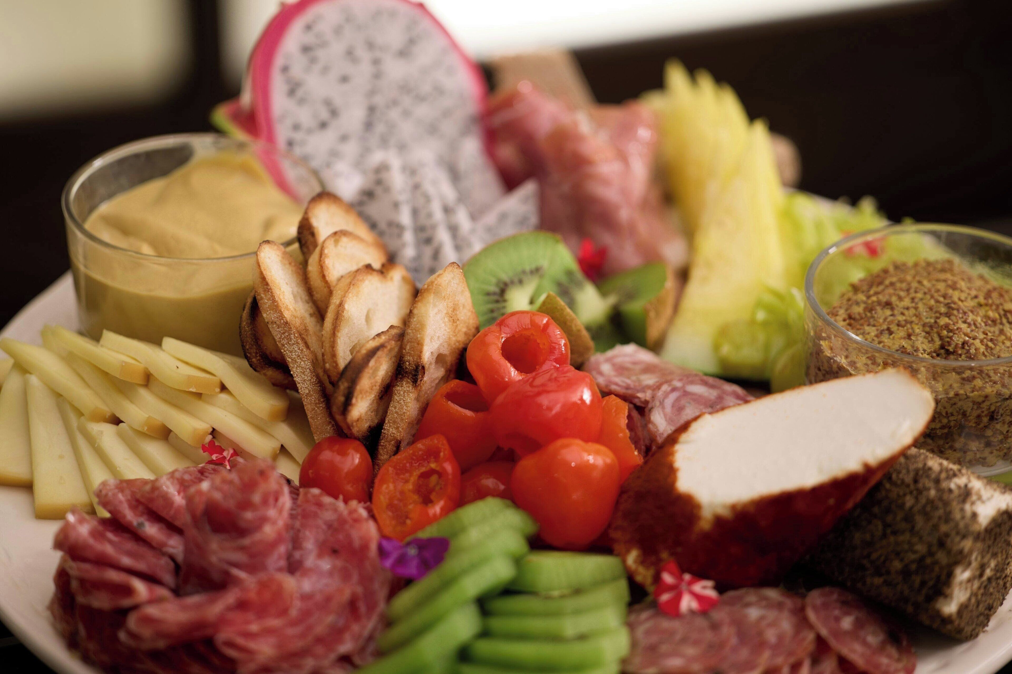 A charcuterie board with various meats, cheeses, fruits, and bread.