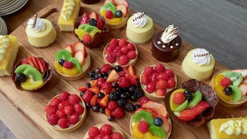 Diversas sobremesas em uma tábua de madeira, incluindo tartes com frutas e cheesecakes.