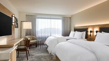 A hotel room with a bed, a desk, a chair, and a television.