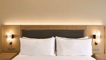 Una cama bien hecha con sábanas blancas, dos almohadas y un cabecero de madera con apliques empotrados.