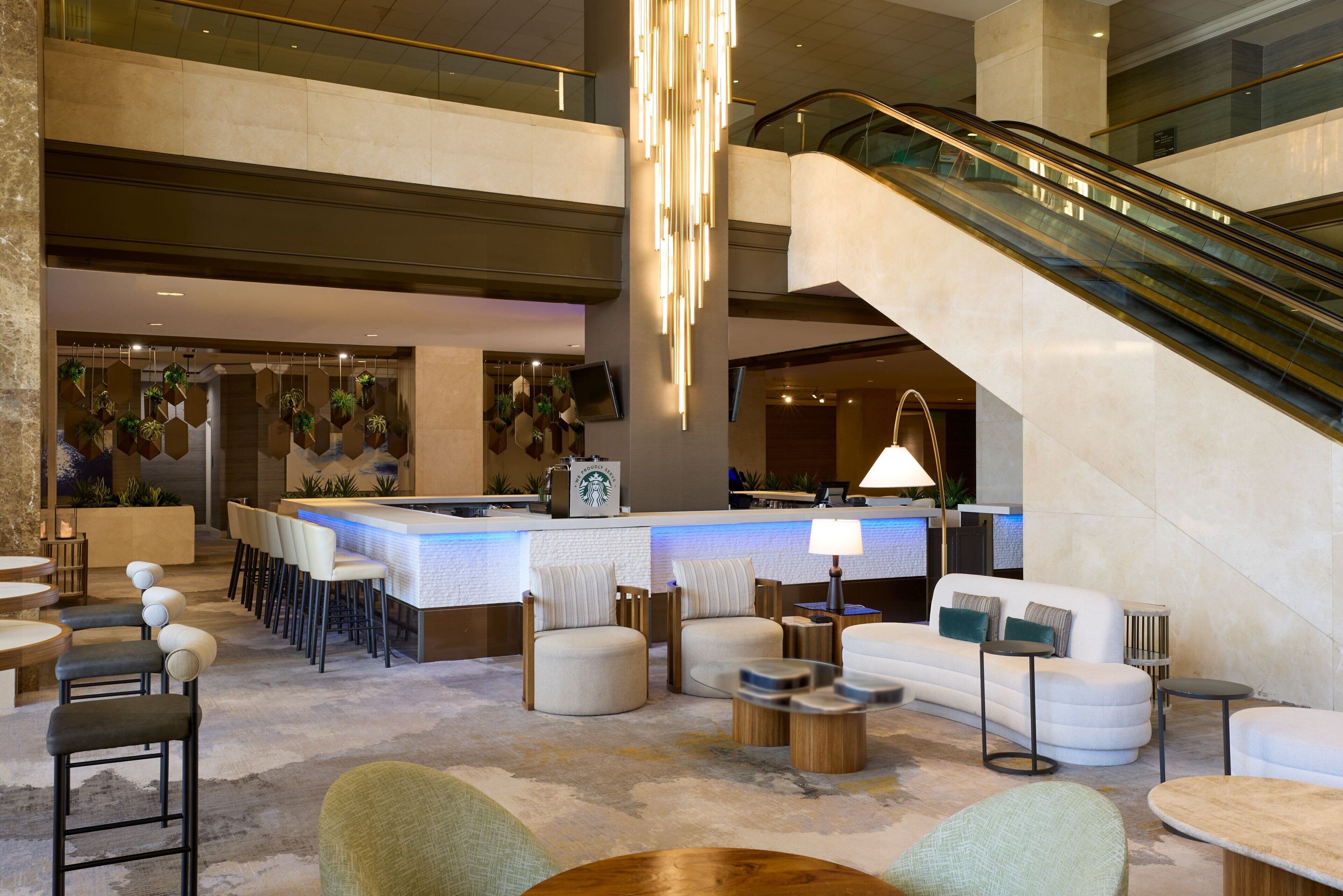 A lobby with a reception desk, seating area, and an escalator.
