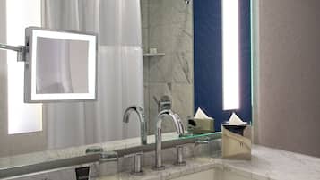 Un bagno con uno specchio grande, un lavandino, un porta asciugamani e una tenda da doccia.