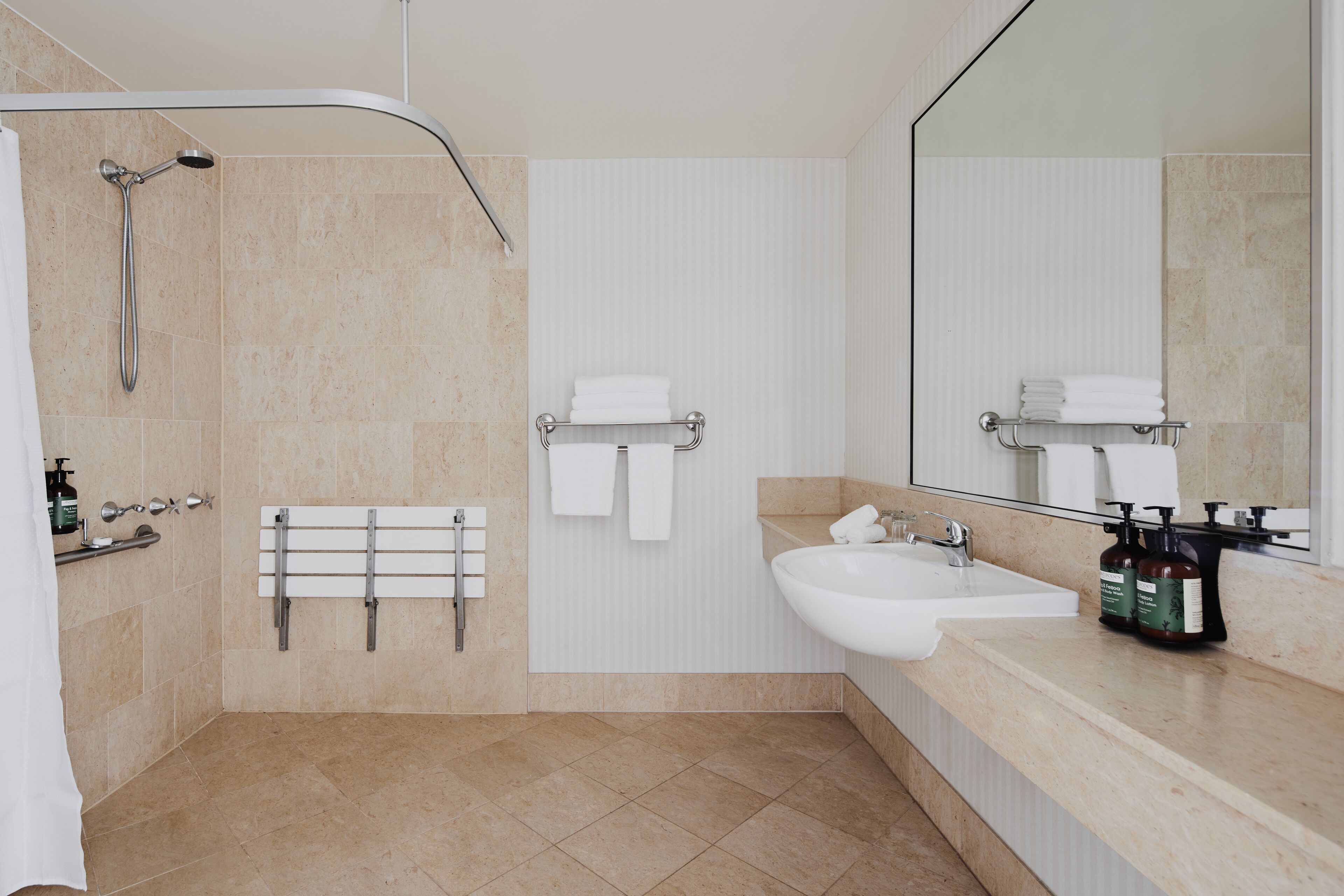 Un baño moderno con ducha, lavamanos, toallero y espejo.