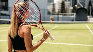 A tennis court with a net and a player holding a racket.