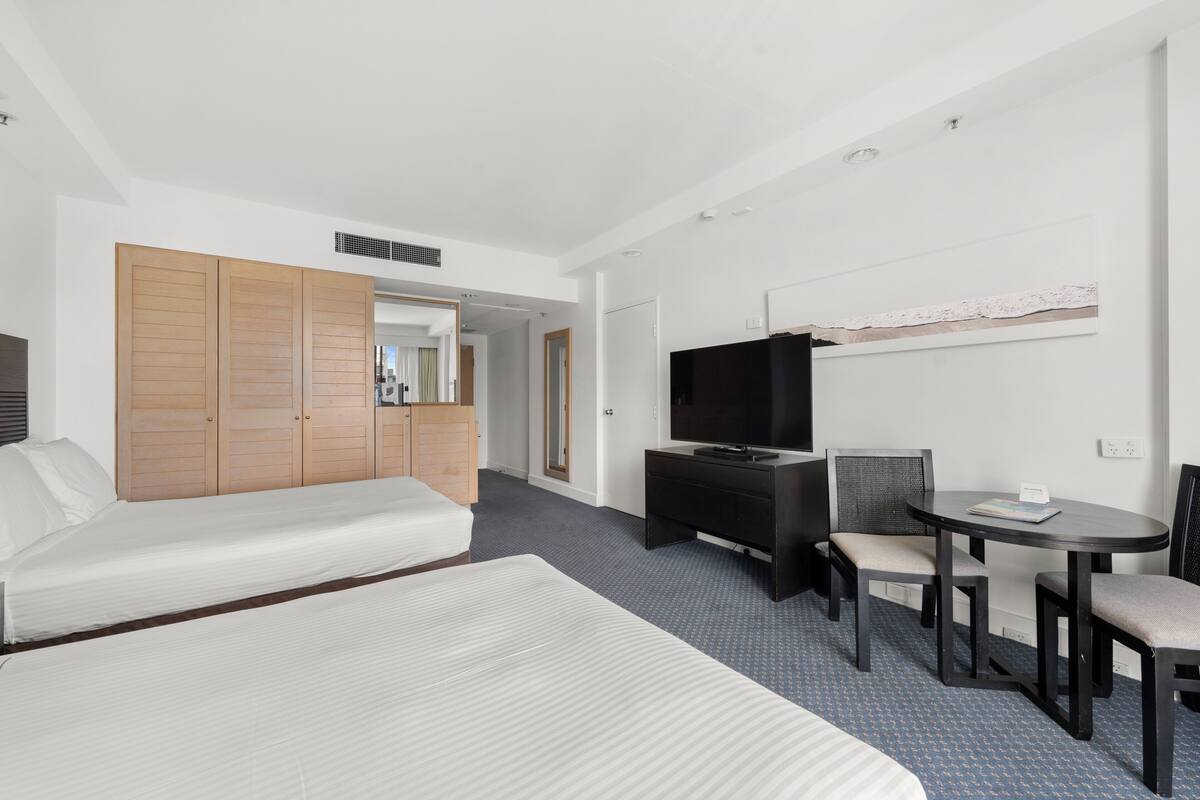 A hotel room with a bed, a sofa, a desk with a chair, a television, and a small table.