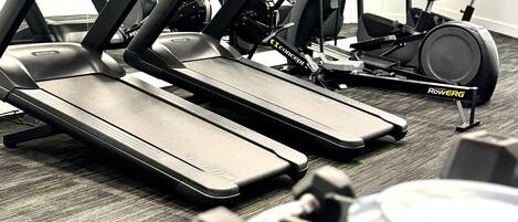 Ein Fitnessstudio mit Laufbändern, Ergometer und Kurzhanteln.