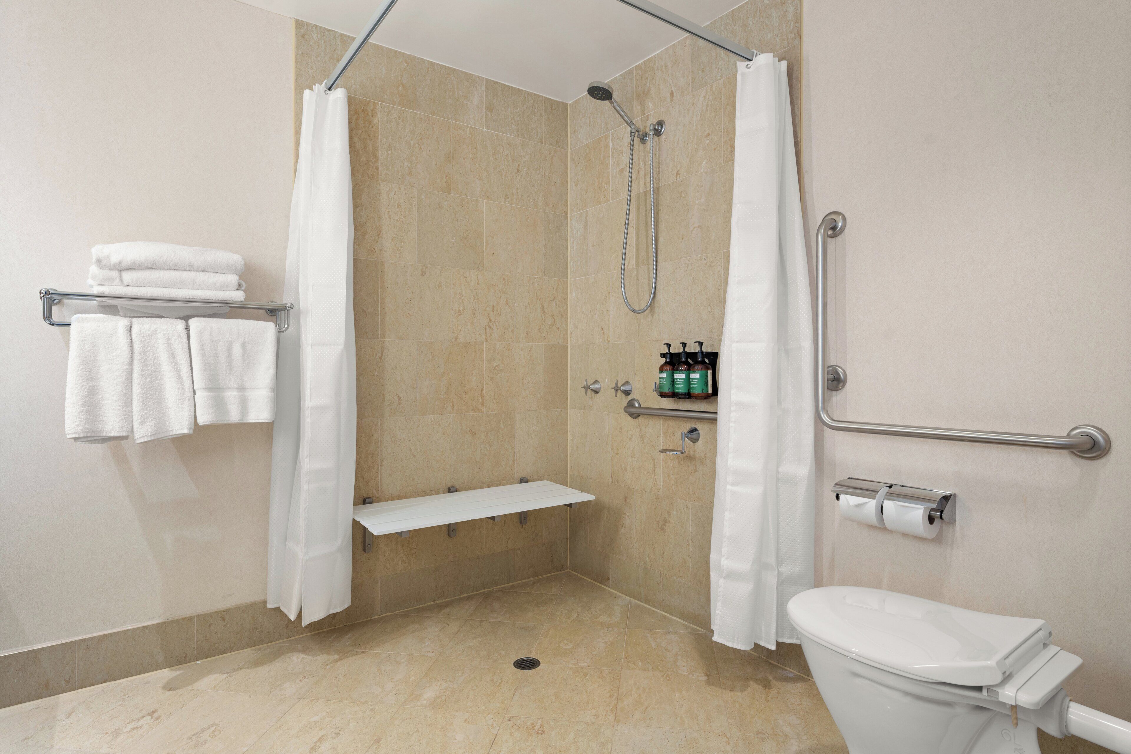 A bathroom with a shower, toilet, and a shelf with towels.