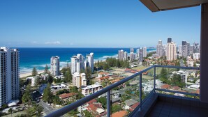 A high-rise building with a balcony overlooking a beach and cityscape.