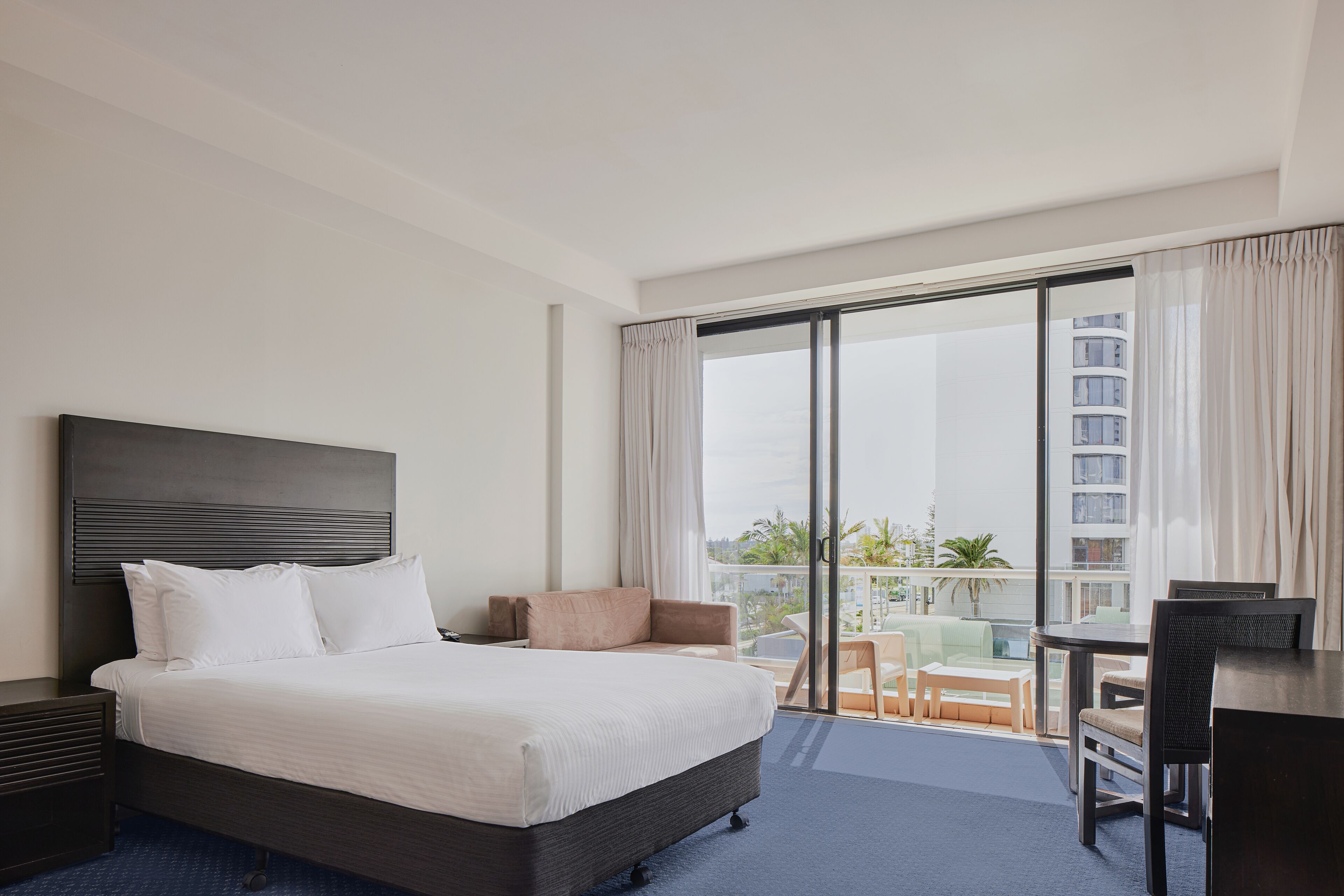 Une chambre d’hôtel avec un grand lit, un bureau et un balcon offrant une vue sur la ville.