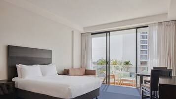 Une chambre d’hôtel avec un grand lit, un bureau et un balcon offrant une vue sur la ville.