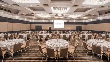 A conference room with round tables, chairs, and a large screen displaying 'CROWNE PLAZA HOTELS & RESORTS'.