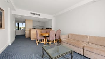 Un soggiorno moderno con tavolino in vetro, divano color beige e zona pranzo con mobili in legno.