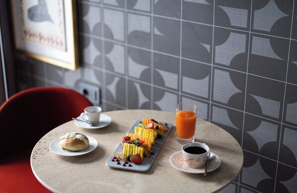 Una mesa con desayuno que incluye un pastel, fruta, jugo y café.