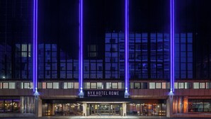 The NYX Hotel Rome facade at night with illuminated vertical lines and the hotel name.