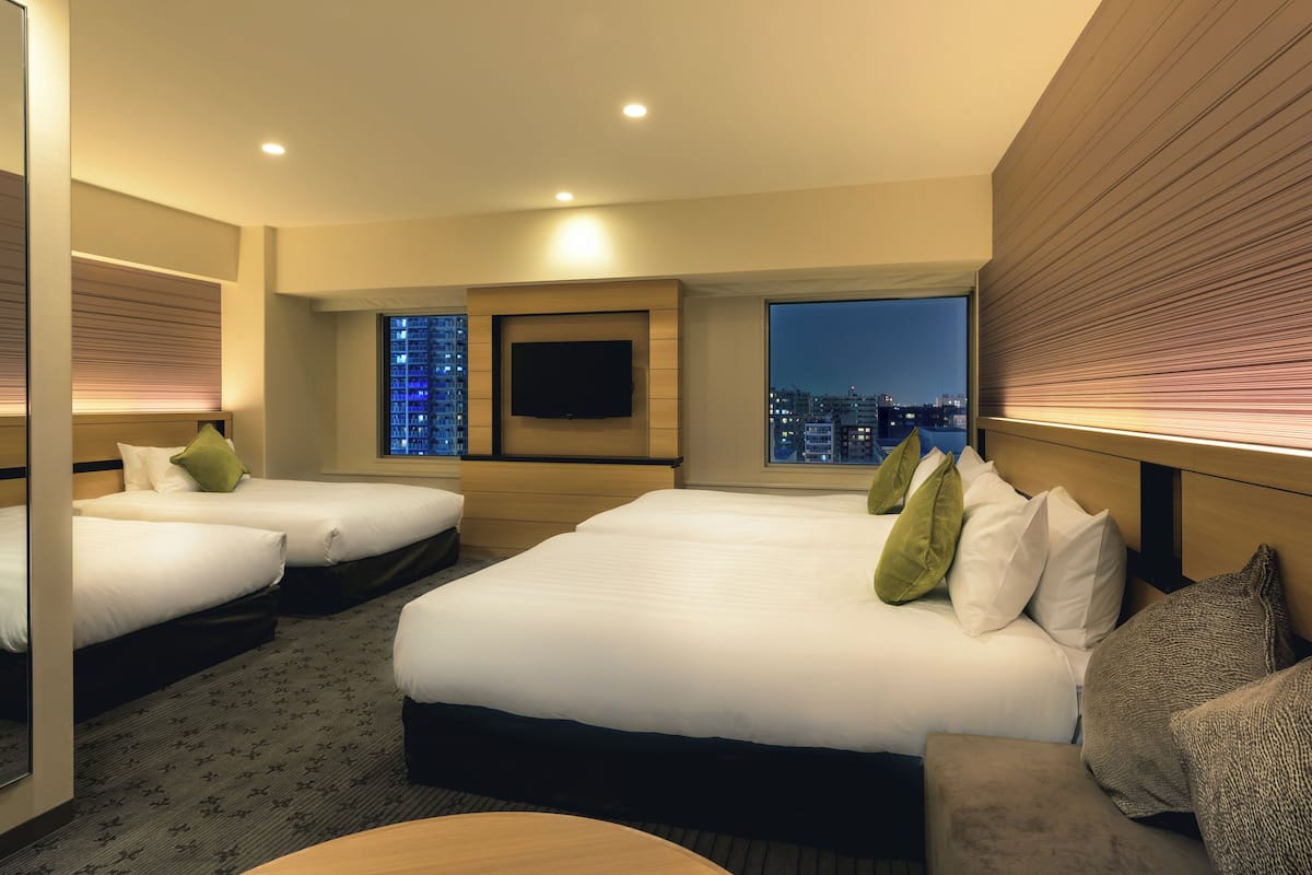 A hotel room with two beds, a TV, a city view, and a wooden headboard.