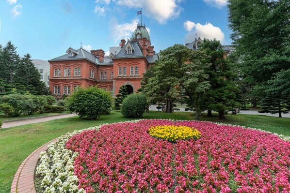 A large building with a prominent dome and a well-maintained garden with colorful flower beds. - ANA Crowne Plaza Sapporo by IHG (Sapporo)