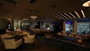 A modern bar area with seating, a decorative light fixture, and a city view through large windows. - ANA Crowne Plaza Sapporo by IHG (Sapporo)