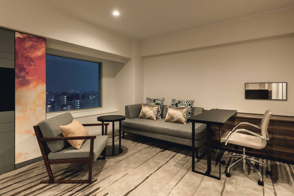 A modern living room with a sofa, armchair, coffee table, and desk.