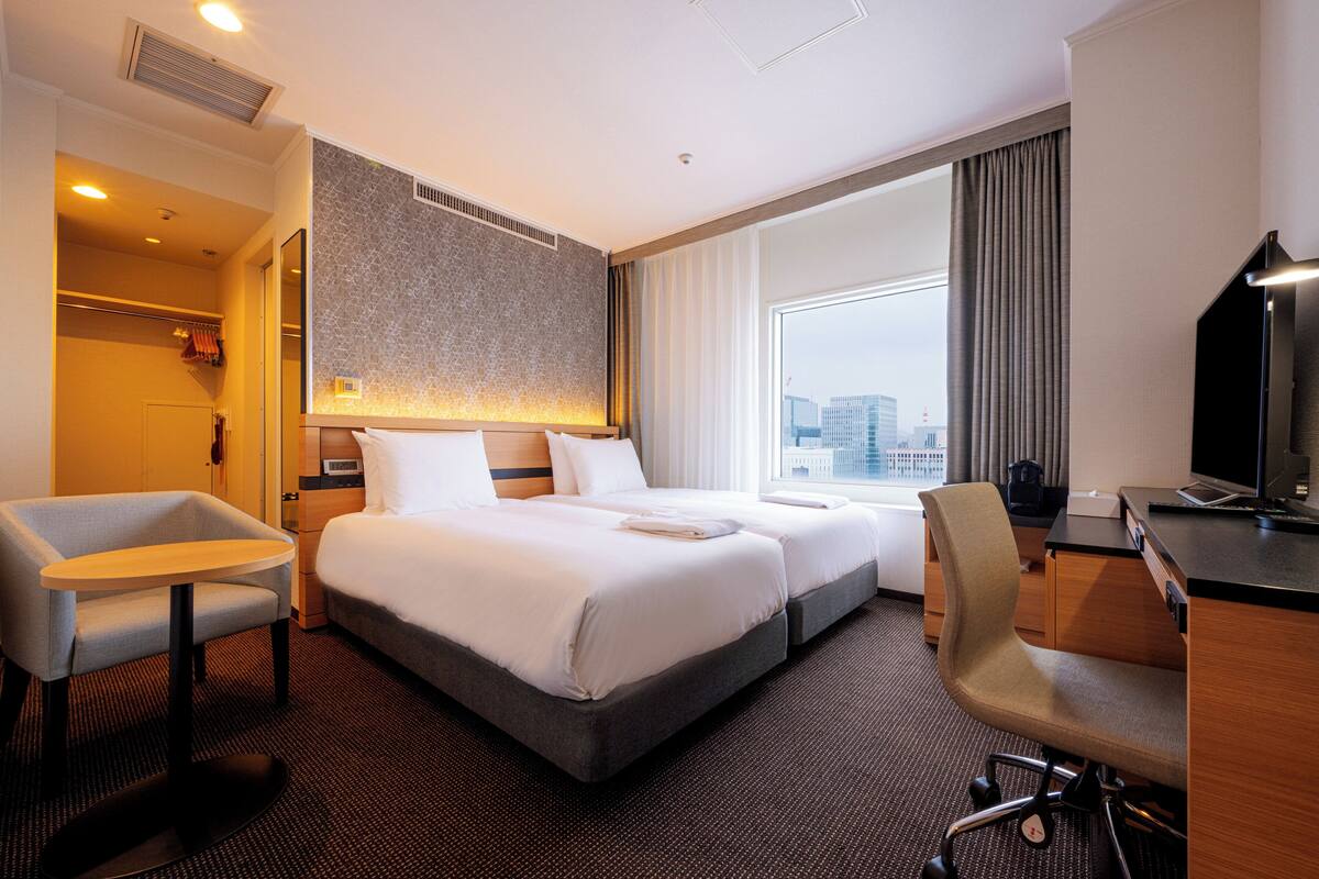 A hotel room with a large bed, a desk, a chair, and a TV.