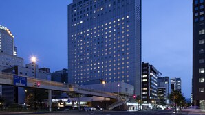A high-rise hotel with a prominent sign at the top, multiple floors, and a pedestrian overpass in the foreground. - ANA Crowne Plaza Sapporo by IHG (Sapporo)