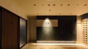 Un área de recepción con una pared oscura, una puerta de madera y un suelo de baldosas.