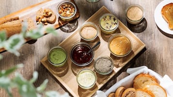 A wooden board with various food items and condiments, including bread, nuts, and jars of spreads.