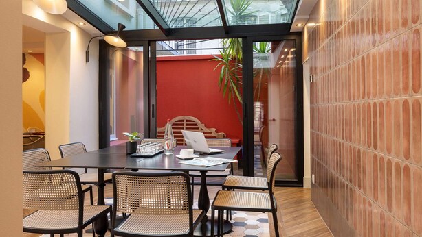 A modern meeting room with a glass ceiling, a red accent wall, and a laptop on the table. - Hotel Elysees 8 (Paris)