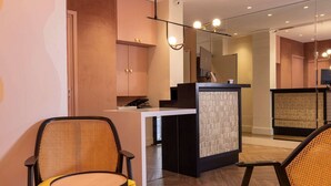 A modern hotel lobby with a reception desk, seating area, and a large mirror. - Hotel Elysees 8 (Paris)