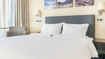 Een hotelkamer met een groot bed, een stoel en twee wandlampen.