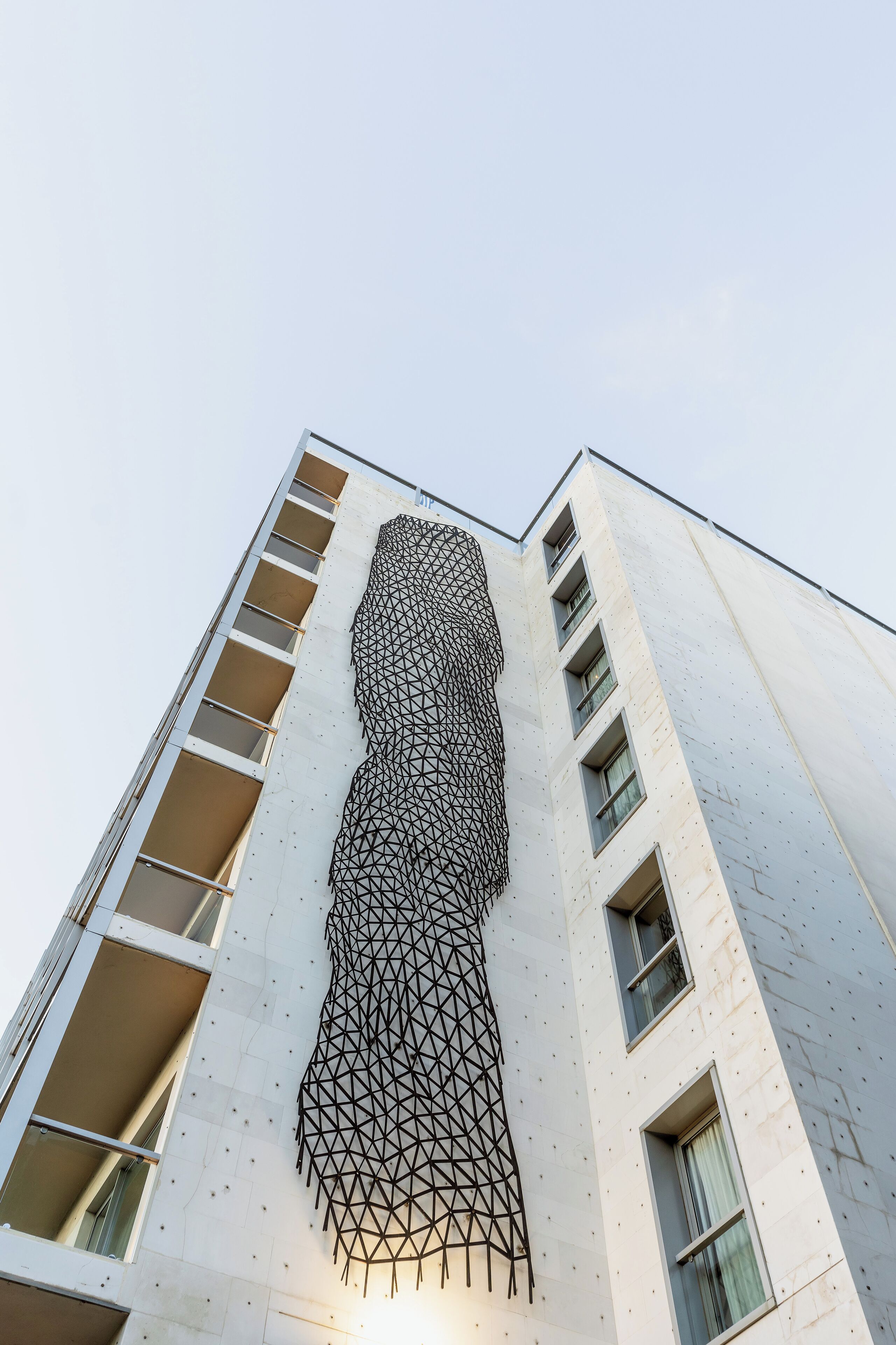 Un edificio moderno con una fachada geométrica distintiva y varios balcones.