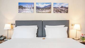 Una habitación de hotel con una cama grande, dos lámparas de noche y tres cuadros en la pared.