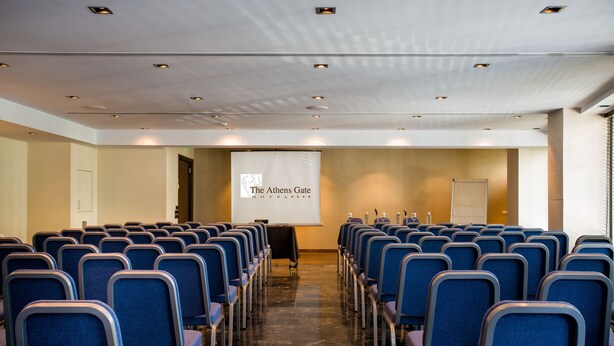 A conference room with rows of blue chairs, a projection screen, and a whiteboard. - Athens Gate Hotel (Athens)