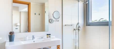 Ein modernes Badezimmer mit Waschbecken, Spiegel und einer Duschkabine aus Glas.