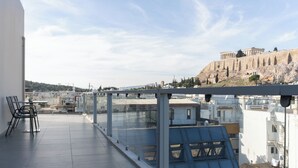 A rooftop terrace with a clear view of a historic building, modern buildings in the background, and a table with chairs.