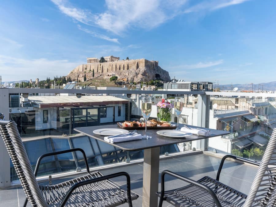Terraza en la azotea con mesa lista para comer, con vistas a una fortificación histórica.