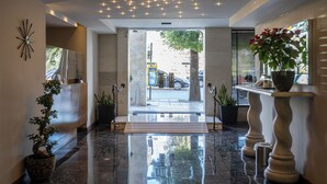 A modern lobby with a polished marble floor, a reception desk, and a large window overlooking the street.