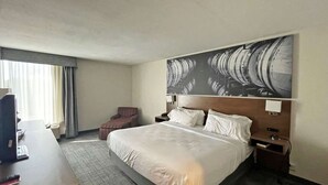 A hotel room with a large bed, a desk, a chair, and a television.