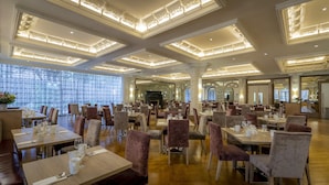 A spacious dining area with multiple tables and chairs, large windows, and ornate ceiling details. - Clayton Hotel Burlington Road (Dublin)