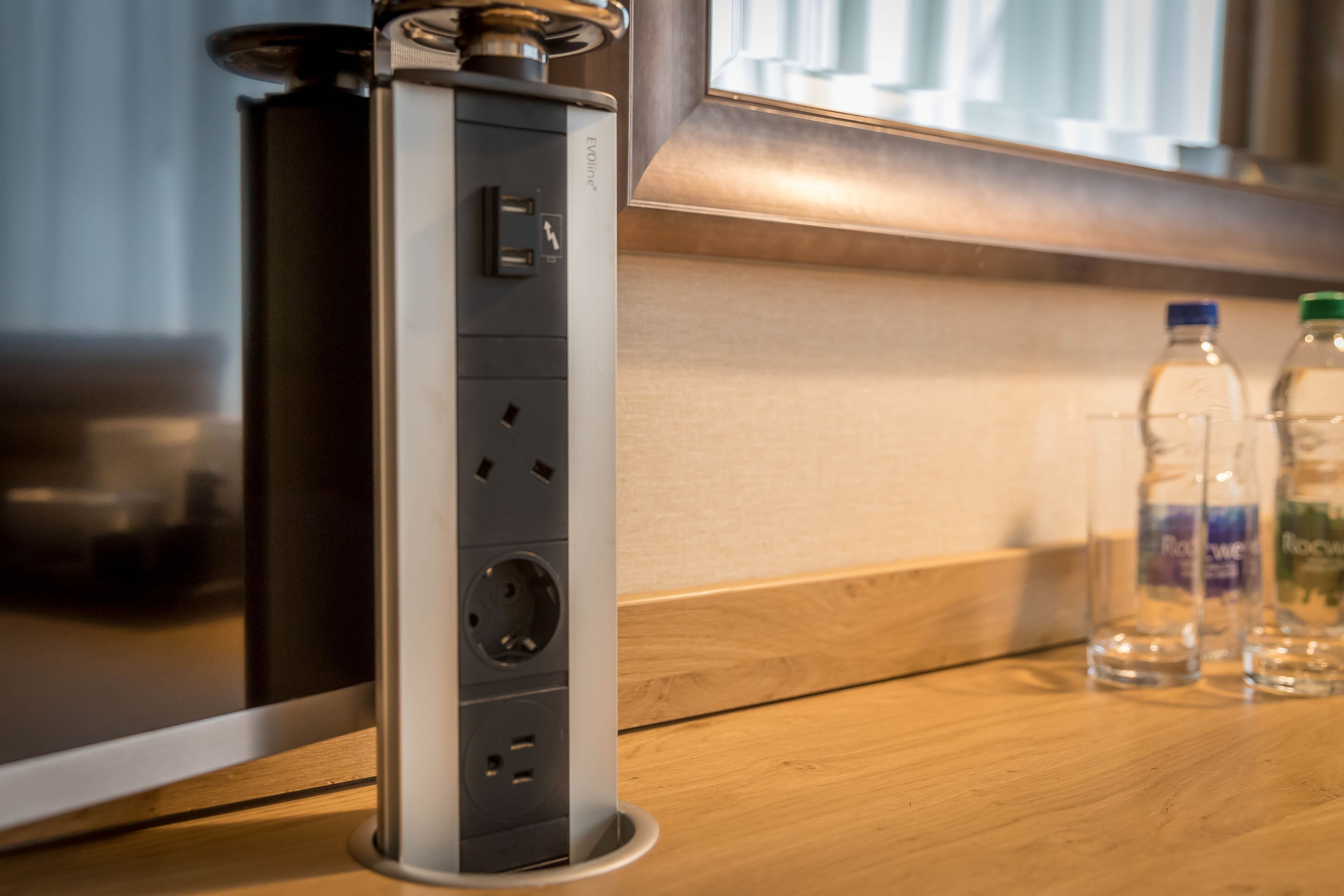 A modern kitchen with a built-in charging station, a wooden countertop, and a window with blinds.