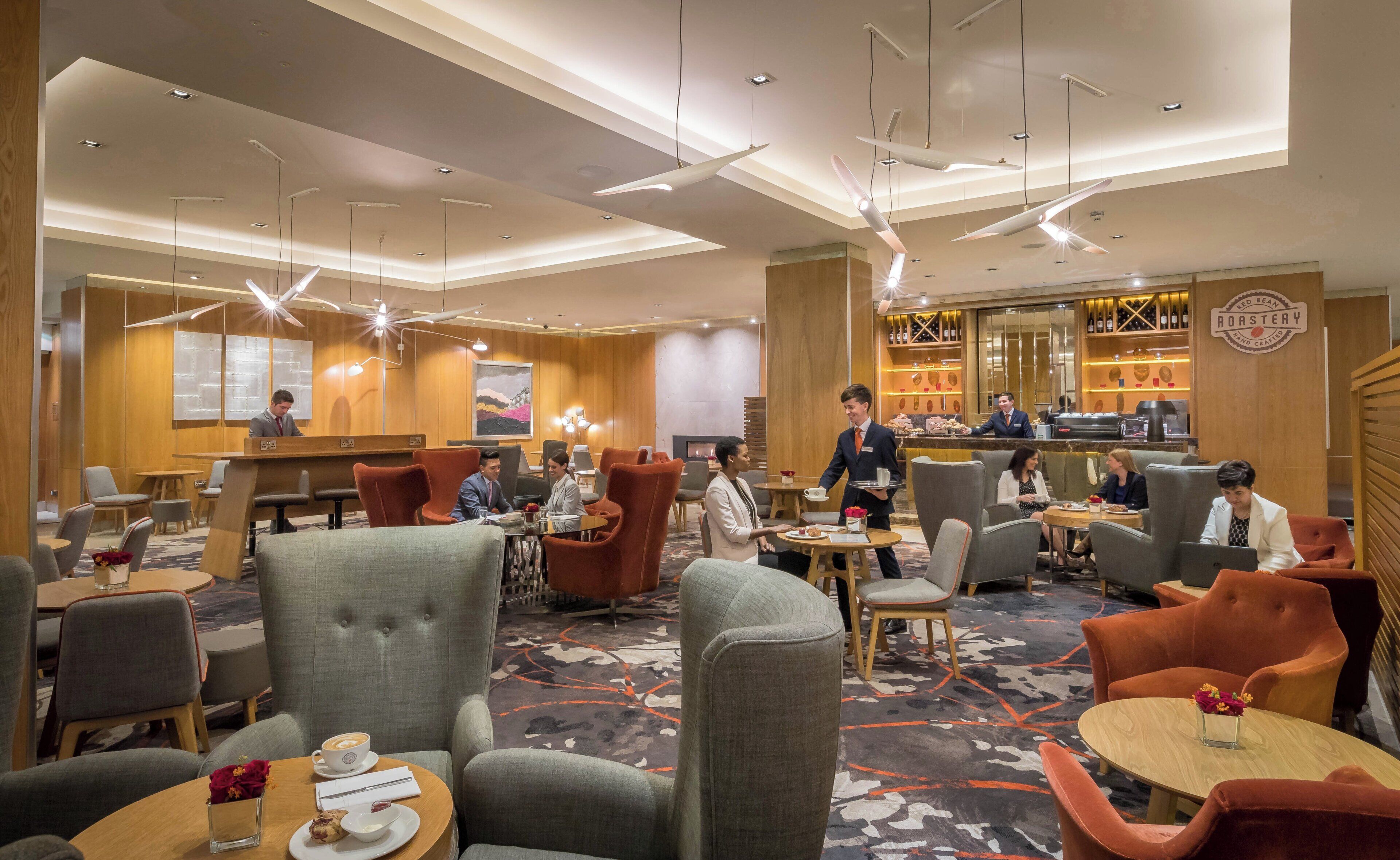 A hotel lobby with seating areas, a bar, and a reception desk.