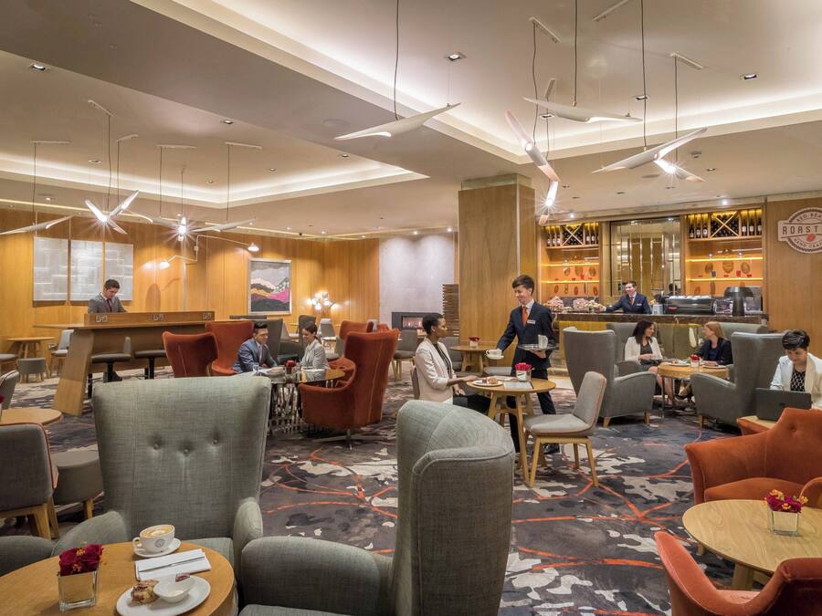 Eine Hotelhalle mit Sitzbereichen, einer Bar und einer Rezeption.
