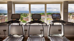 Three treadmills in a room with large windows overlooking a cityscape. - Clayton Hotel Burlington Road (Dublin)