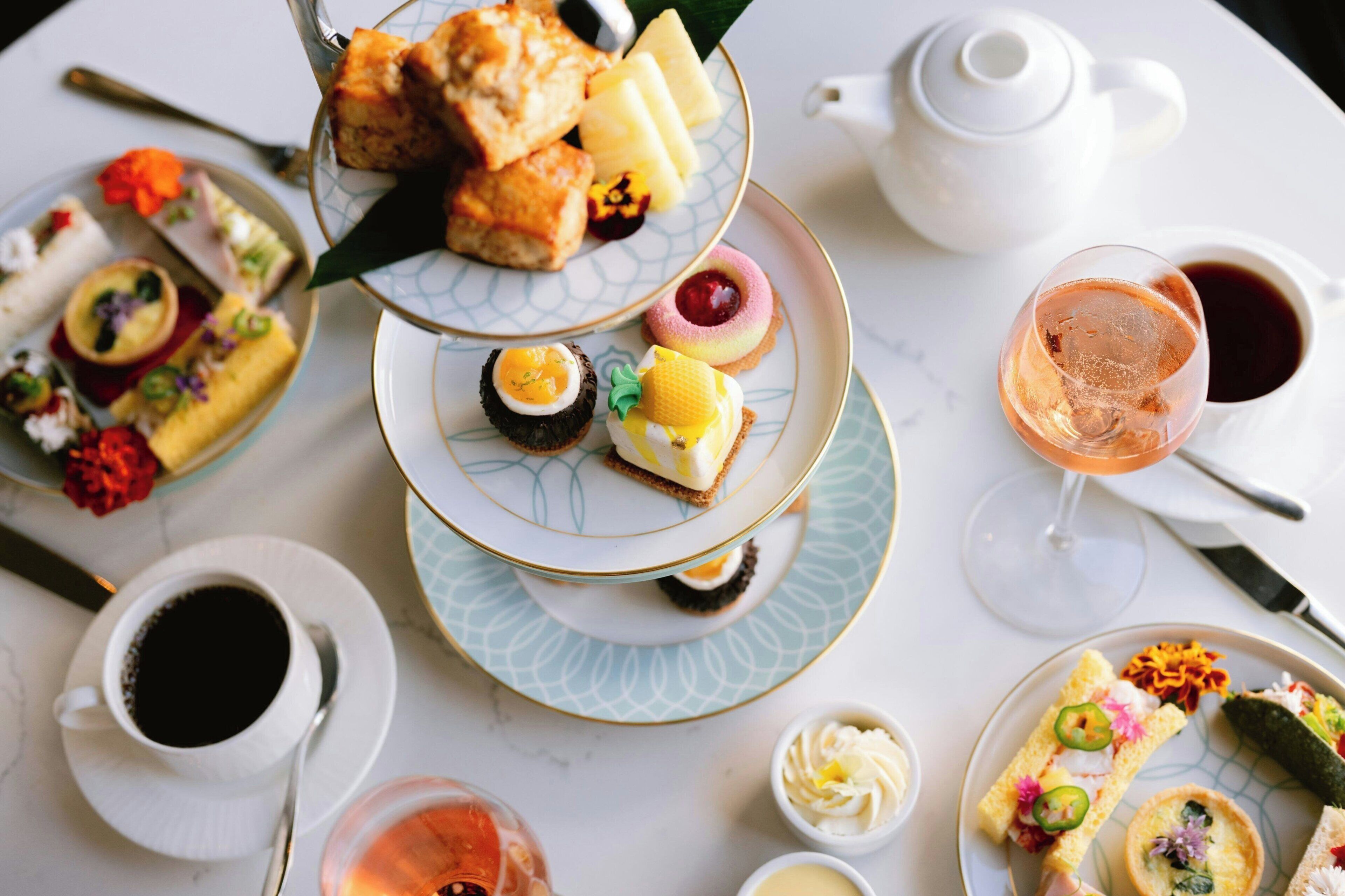 A table with various pastries, a teapot, and a cup of coffee.