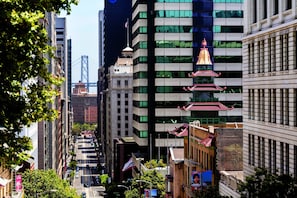 A city street lined with modern buildings, including a prominent tower with a bell and a traditional pagoda-style structure.
