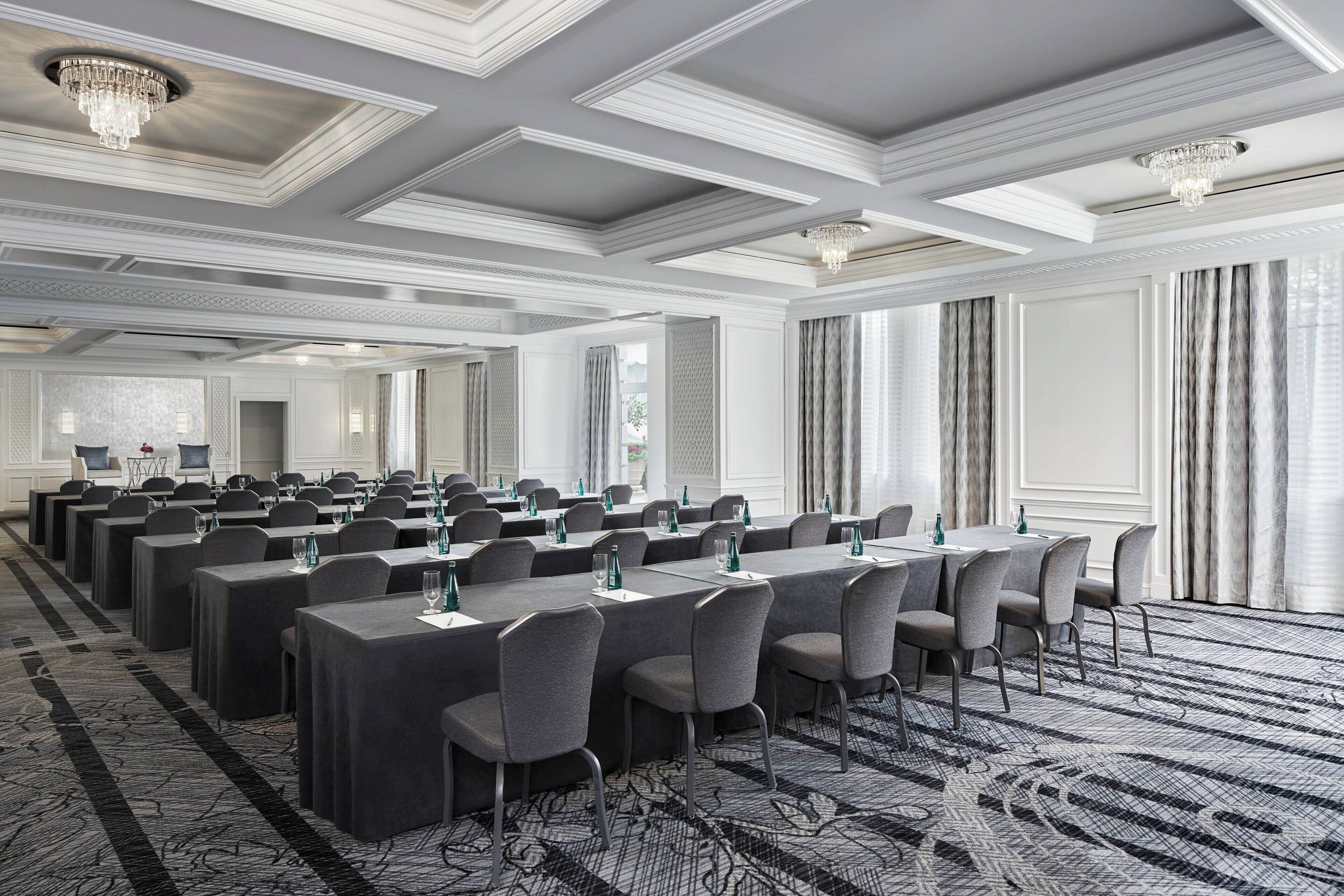 A conference room with long tables, chairs, and a patterned carpet.
