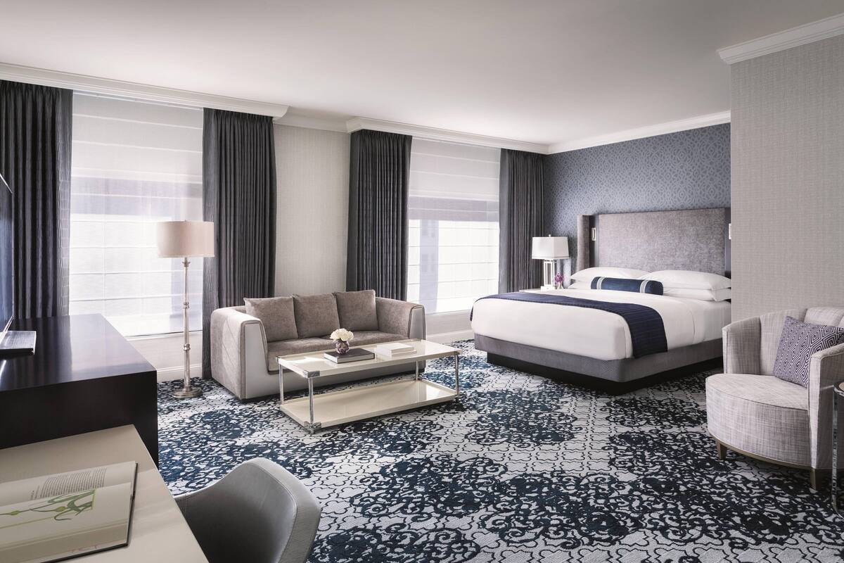 A hotel room with a large bed, a sofa, a desk, and a coffee table.