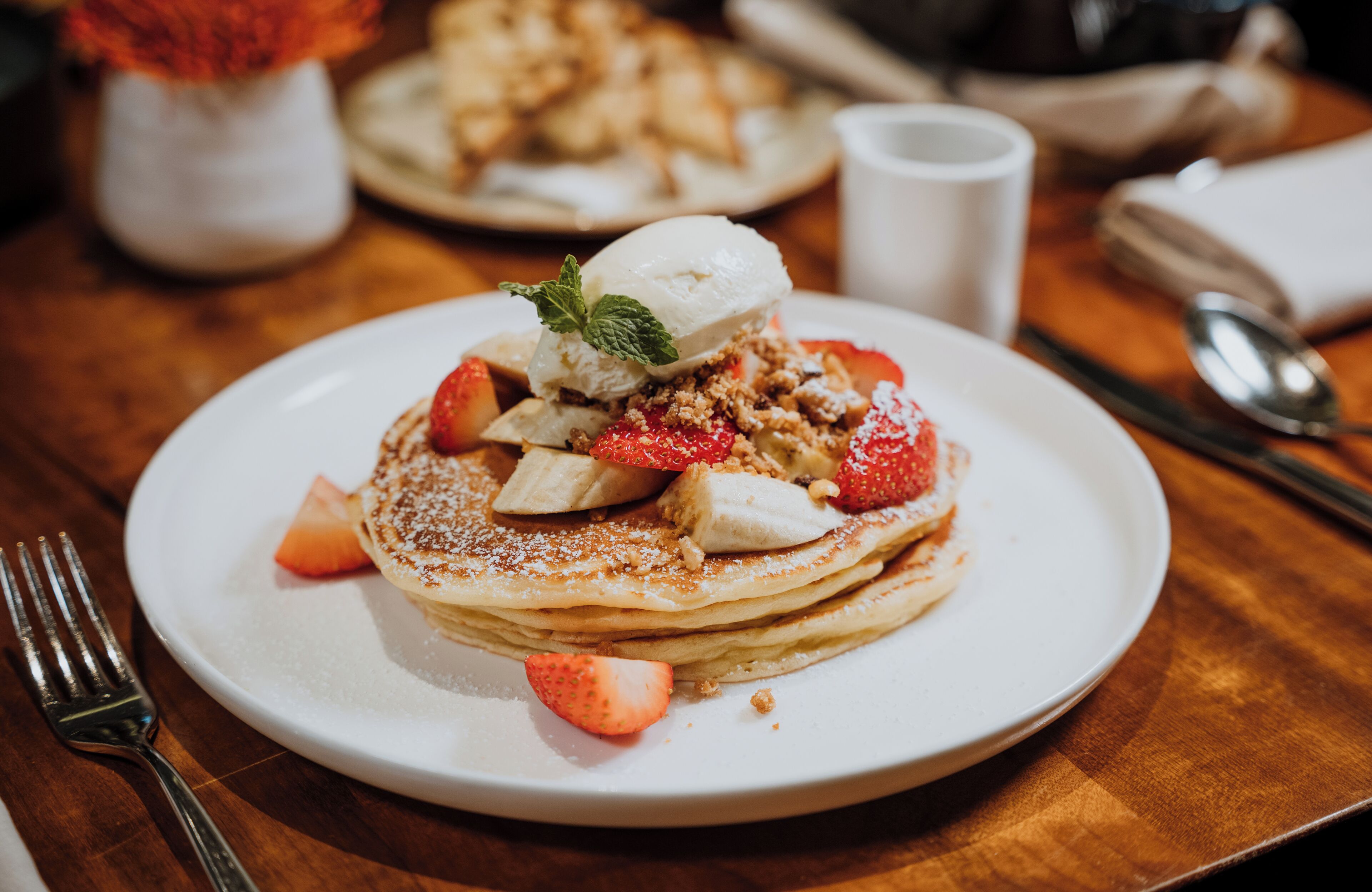 Ein Teller Pfannkuchen mit Erdbeeren, Bananenscheiben und einer Kugel Eis.
