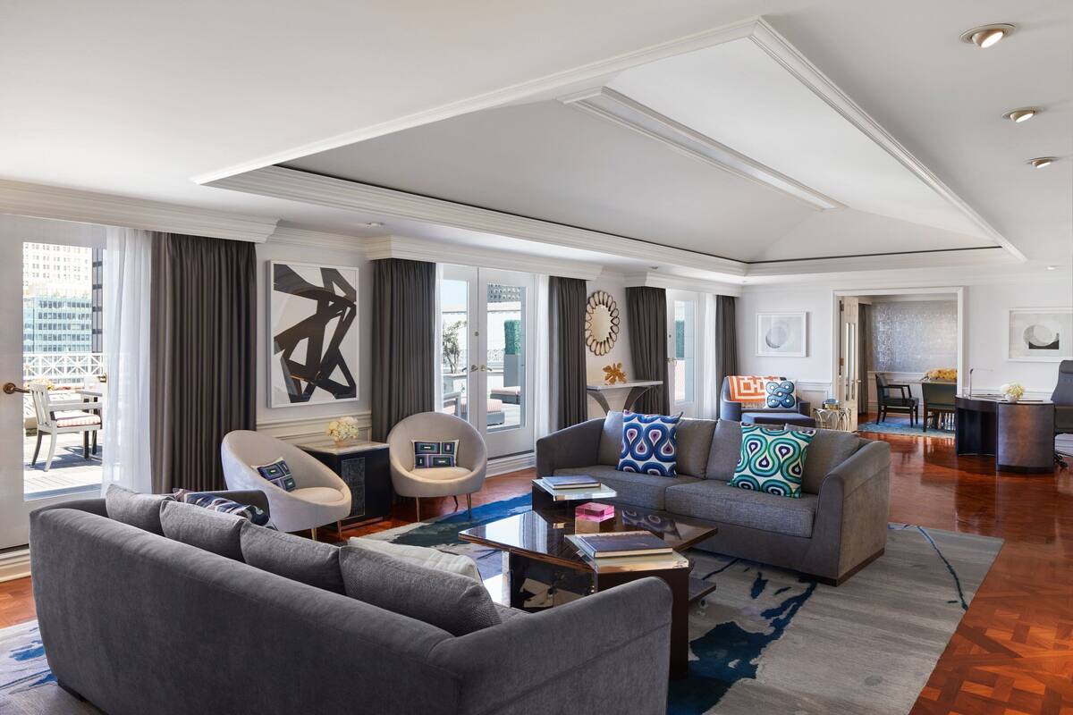 A spacious living room with a grey sofa, armchairs, and a coffee table.